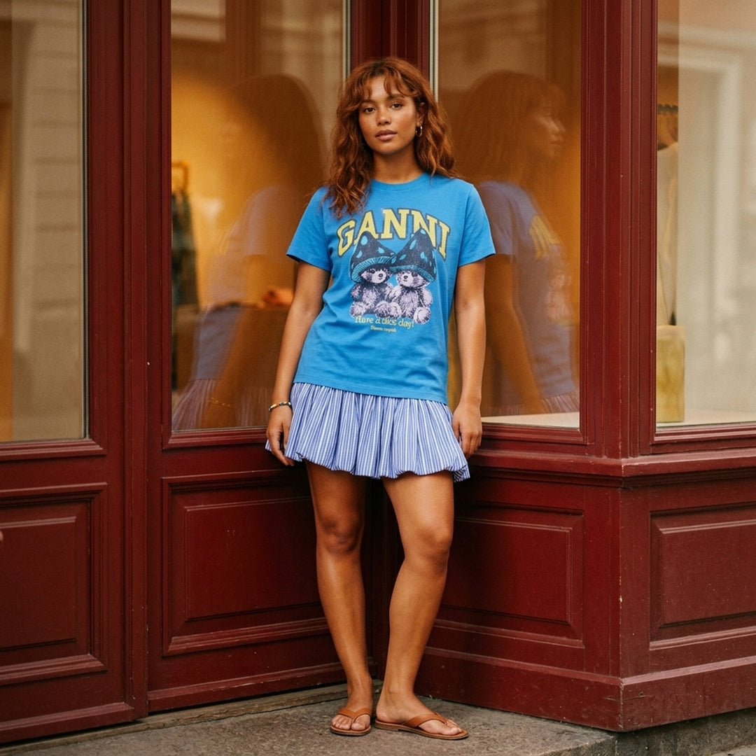 Ganni Heavy Jersey Baby Fit Tee in bright blue with collegiate Ganni logo, mushroom bear graphic, and 'Have a nice day! Please recycle' slogan print on the chest - lifestyle