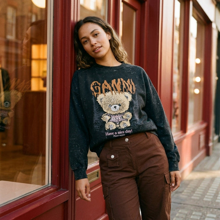 Ganni Teddy Forest Crewneck Sweatshirt in acid-washed black with dripping orange Ganni lettering and teddy bear mascot graphic on the front - lifestyle