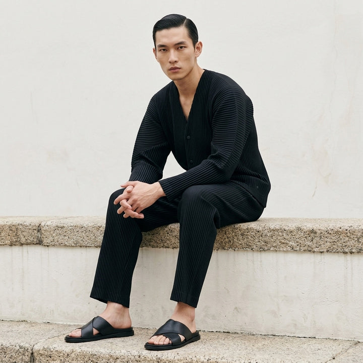 Homme Plissé Issey Miyake Basic Button Cardigan in black, featuring signature permanent accordion pleating across the body and long sleeves, with a deep V-neckline and four snap-button front closure - lifestyle