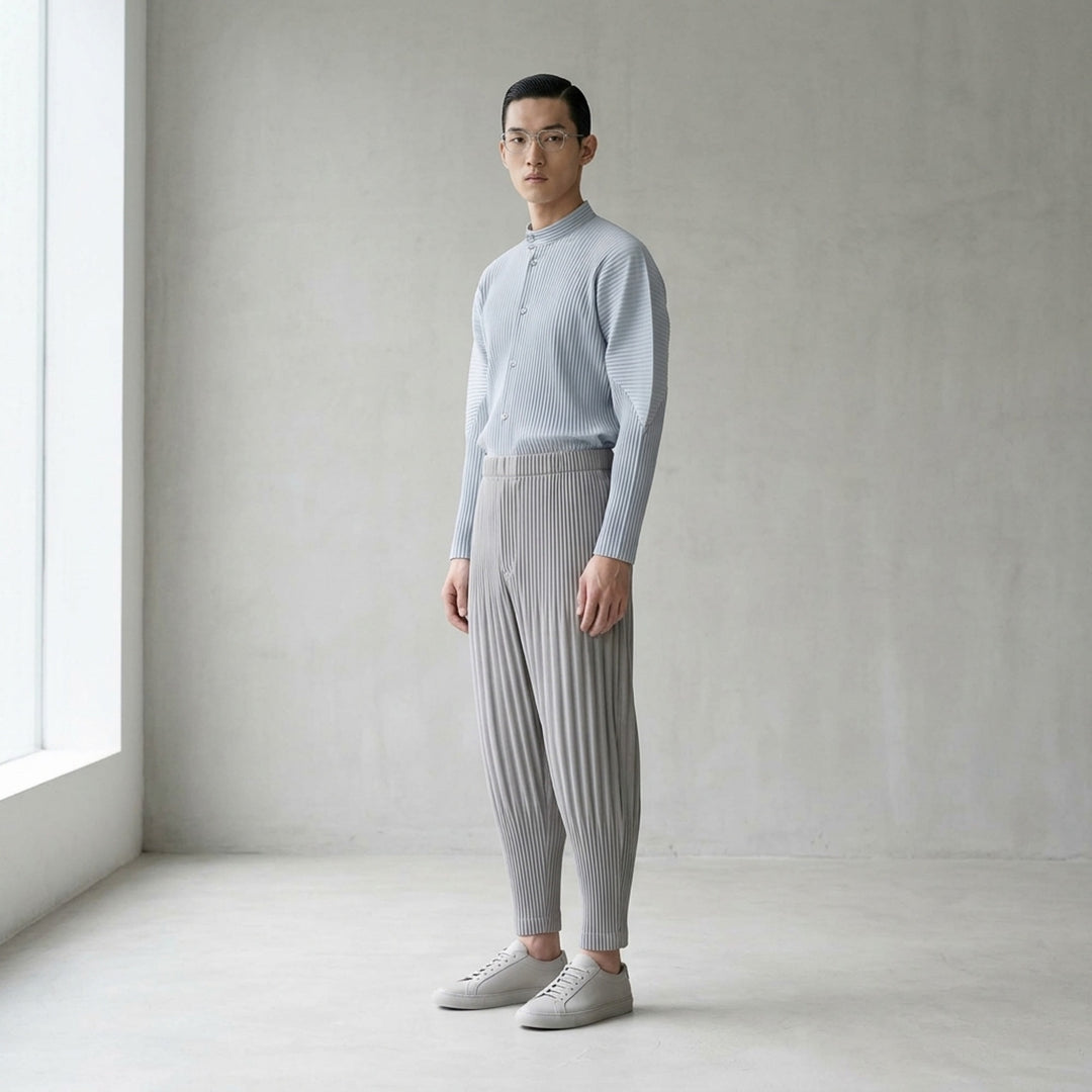 Homme Plissé Issey Miyake Basic Fluffy Long Pants in light grey, featuring signature all-over pleating, a relaxed balloon-tapered silhouette, elasticated waistband, and ribbed ankle cuffs - lifestyle
