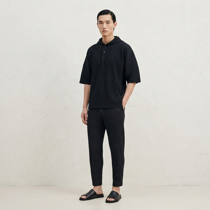 Homme Plissé Issey Miyake Compleat Pleated Trousers in black, shown flat with all-over permanent pleating and elasticated waistband - lifestyle