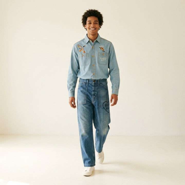 Human Made baggy denim pants in washed mid-blue with oversized patch pockets and a heart logo print on the leg, shown from the front - lifestyle