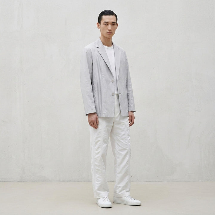 Pale grey IM Men Air Pleats jacket with notched lapels, vertical pleated panels and a two-button front, shown on a white background - lifestyle