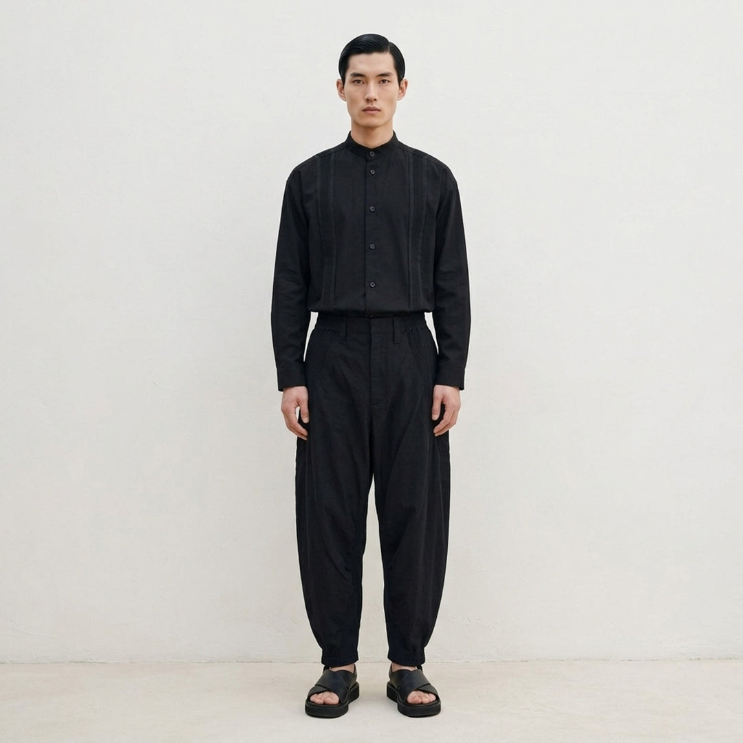 IM MEN Clay Woven Pants in deep navy — drop-crotch silhouette with elasticated waistband, voluminous thigh, and tapered cuffed ankles, front view on white background - lifestyle