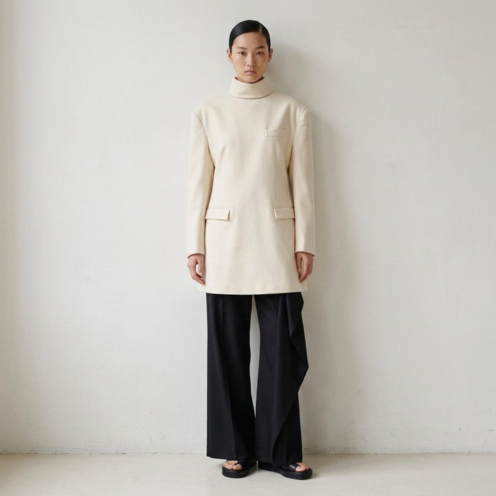 Issey Miyake burgundy tunic with funnel neck, structured shoulders, chest welt pocket and two flap pockets, shown from the front - lifestyle