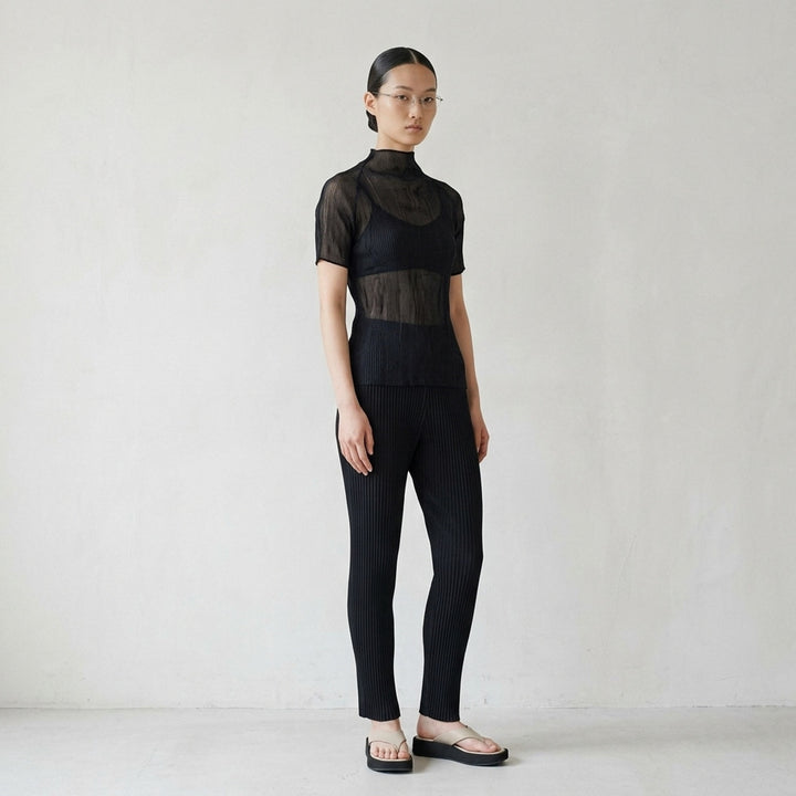 Issey Miyake Chiffon Twist Short Sleeve Shirt in black, featuring sheer pleated fabric and a high mock-neck collar, shown from the back on a mannequin - lifestyle