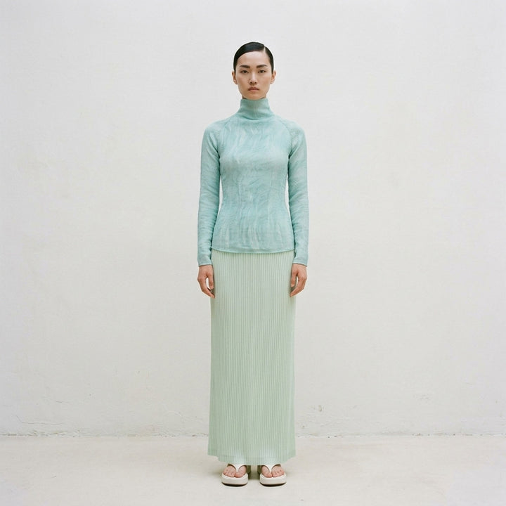 Rear view of Issey Miyake Chiffon Twist 2 woven top in grey, featuring fine horizontal pleating, a high funnel neck, and long fitted sleeves on a mannequin - lifestyle