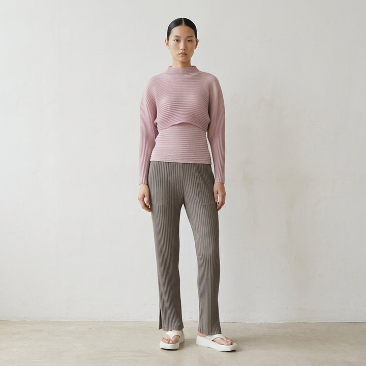 Issey Miyake Hatching Pleats pleated pants in muted taupe-grey with elasticated waist, patch pockets and straight leg, front view - lifestyle