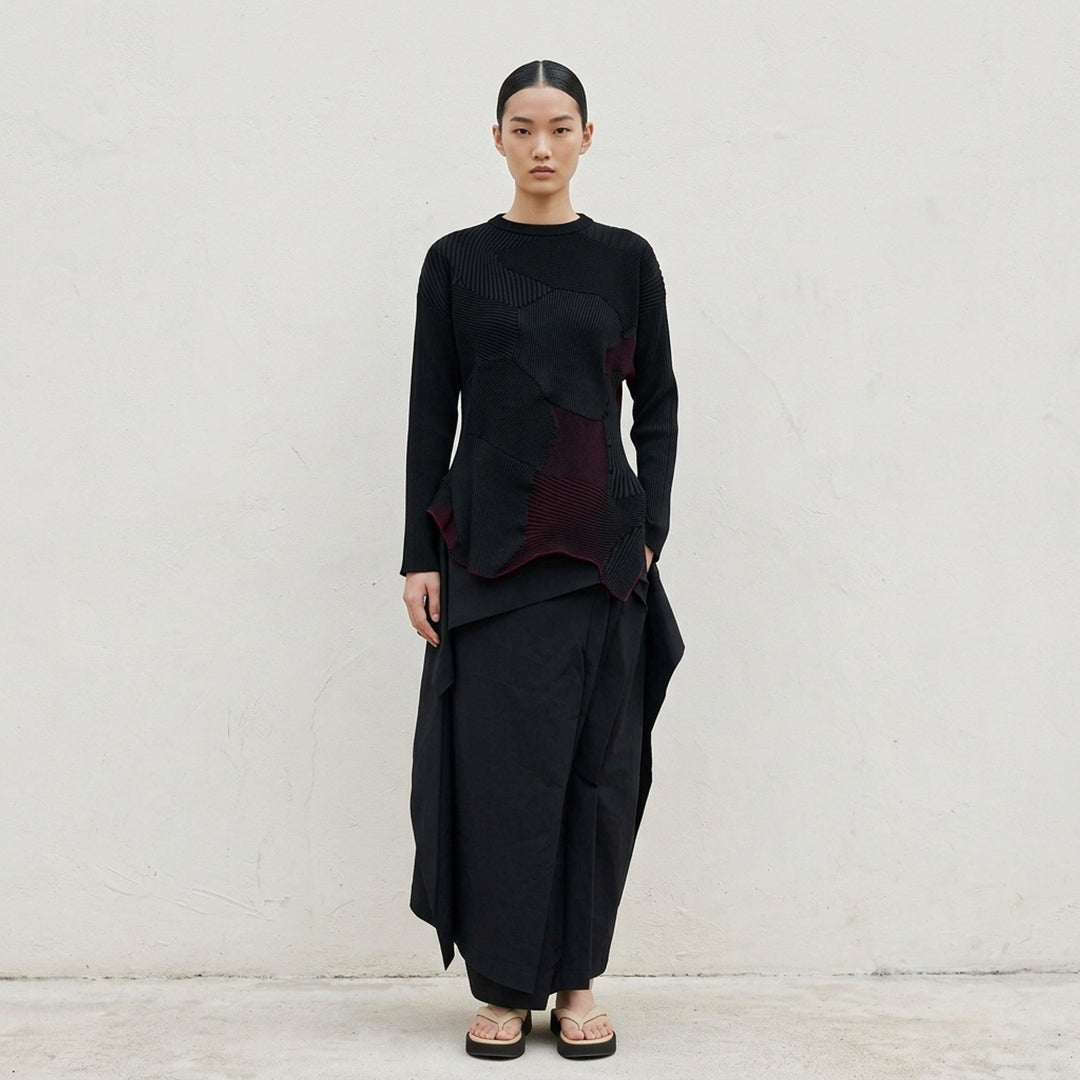 Issey Miyake KONE KONE black knit top with multi-directional ribbed panels, asymmetric pointed hem, and long sleeves — rear view on white background - lifestyle