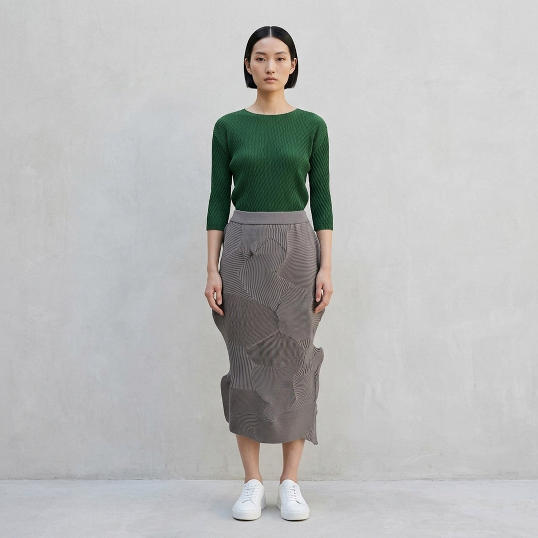 Issey Miyake KONE KONE black sculptural ribbed knit skirt with three-dimensional alternating pleated panels and an asymmetric hem, shot flat on a white background - lifestyle