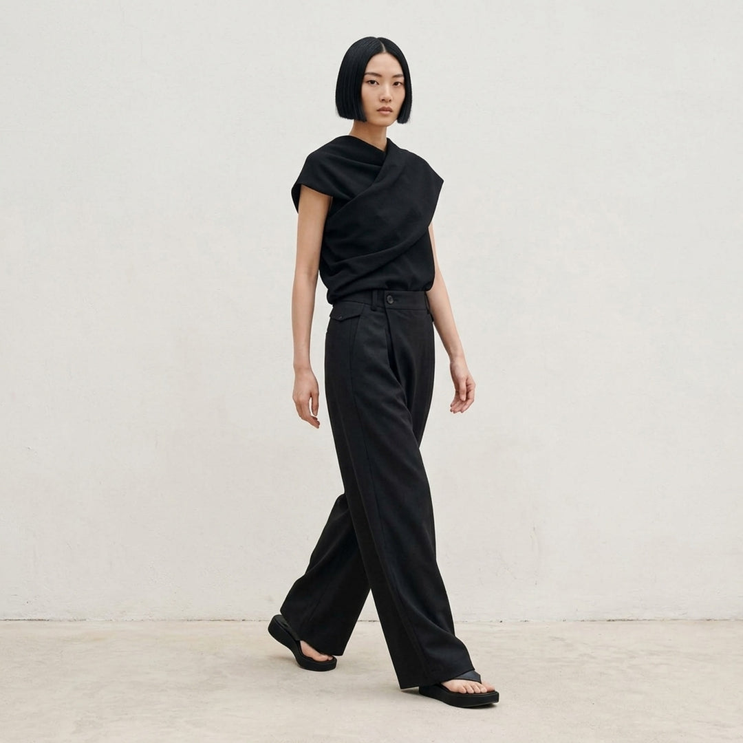 Issey Miyake Lustrous Wool Pants in black, featuring a wide-leg cropped silhouette, double front pleats, button-tab waistband, and welt rear pockets with button tab detail - lifestyle