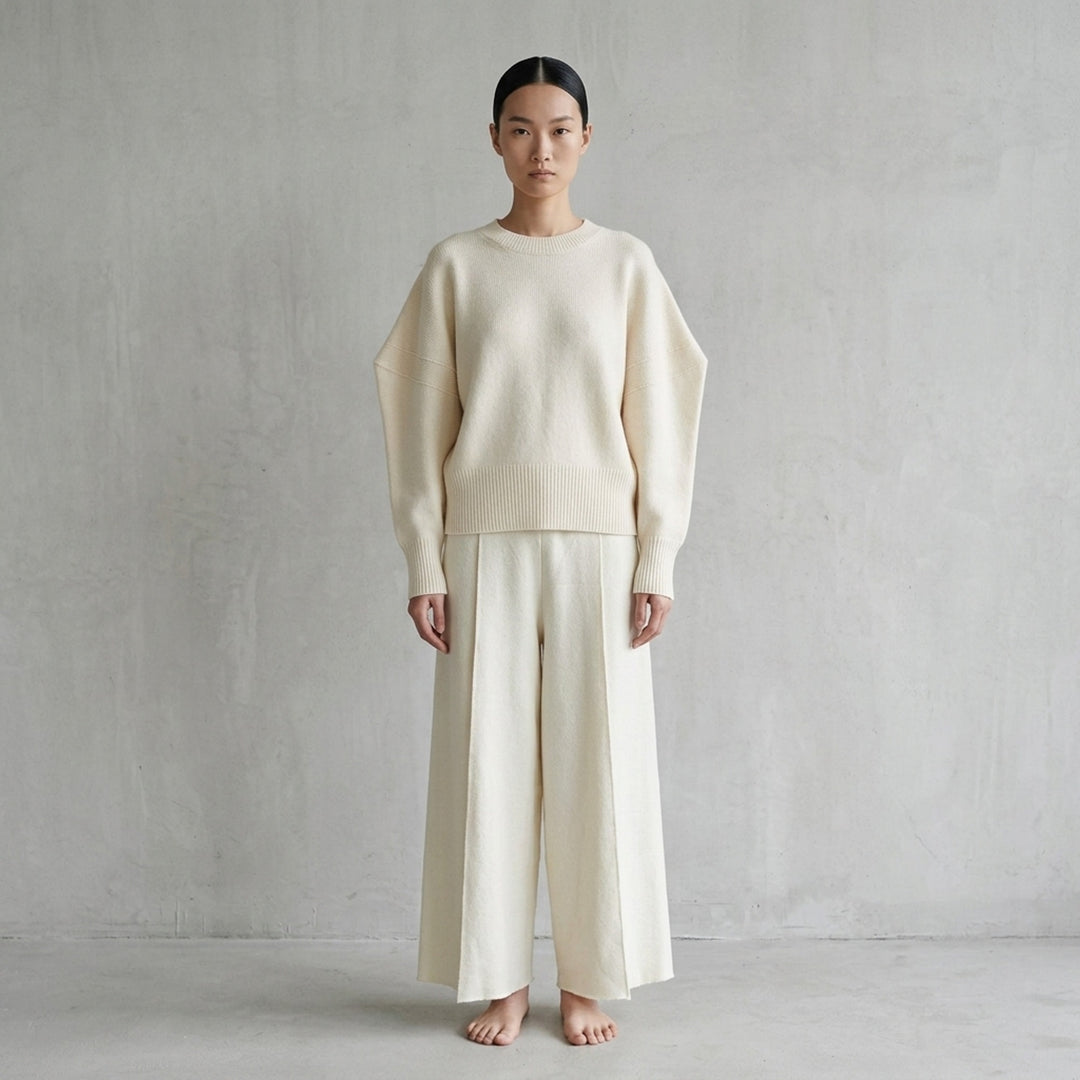 Issey Miyake O KNIT black crew neck sweater with sculptural rounded sleeves and ribbed hem and cuffs, shown from the front - lifestyle
