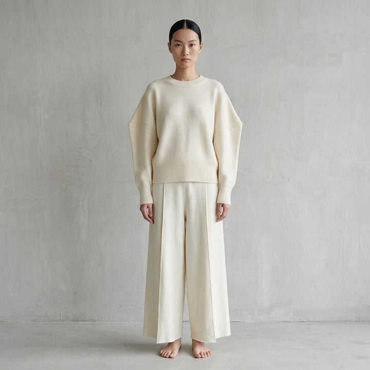 Issey Miyake O KNIT black crew neck sweater with sculptural rounded sleeves and ribbed hem and cuffs, shown from the front - lifestyle