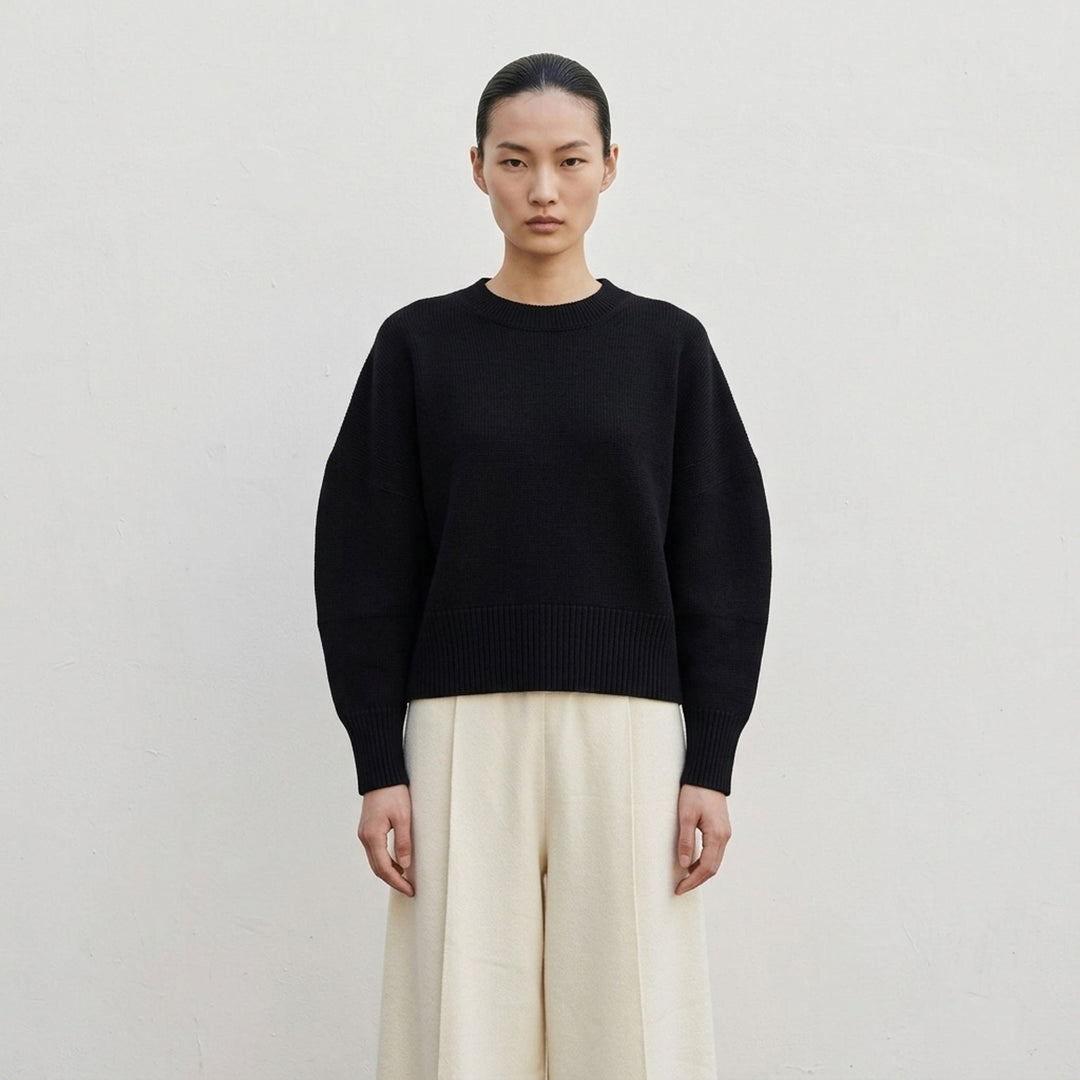 Issey Miyake O KNIT black crew neck sweater with sculptural rounded sleeves and ribbed hem and cuffs, shown from the front - lifestyle