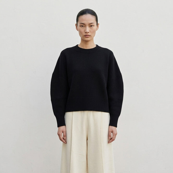 Issey Miyake O KNIT black crew neck sweater with sculptural rounded sleeves and ribbed hem and cuffs, shown from the front - lifestyle