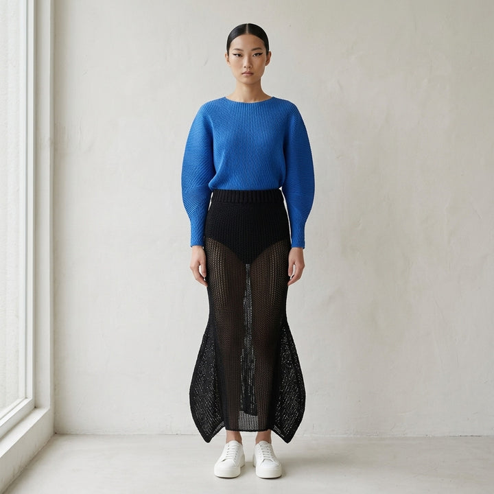 Issey Miyake Panini Pulled black open-weave sheer knit midi skirt with ribbed waistband and flared petal-shaped side panels, front view - lifestyle
