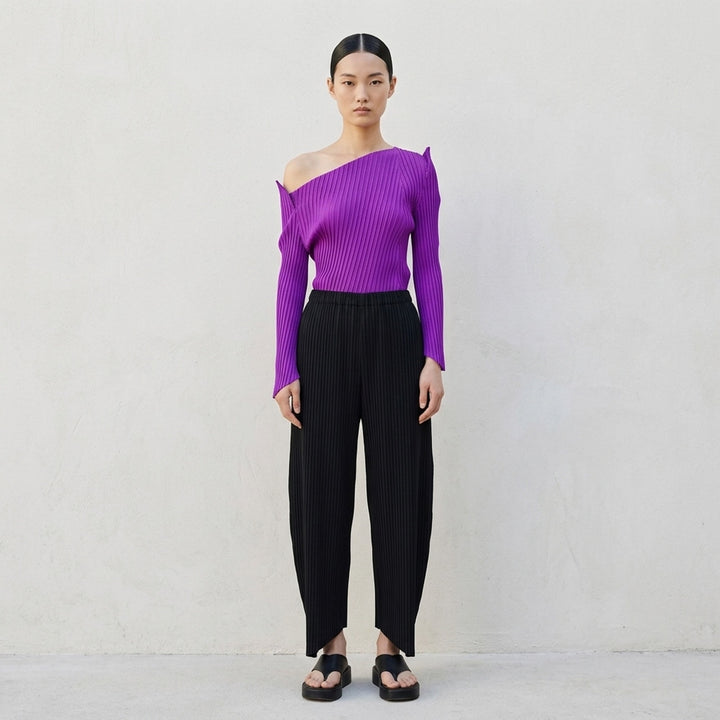 Issey Miyake Tubular Pleated Top in black, featuring vertical accordion pleating, an off-shoulder asymmetric neckline, long sleeves with pointed cuffs, and an angled hem - lifestyle