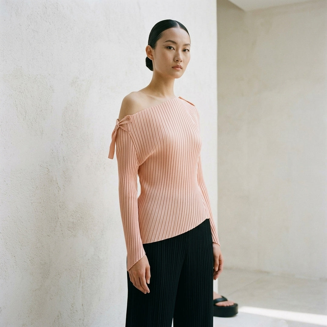 Issey Miyake Tubular Pleated Top in black, featuring vertical accordion pleating, an off-shoulder asymmetric neckline, long sleeves with pointed cuffs, and an angled hem - lifestyle