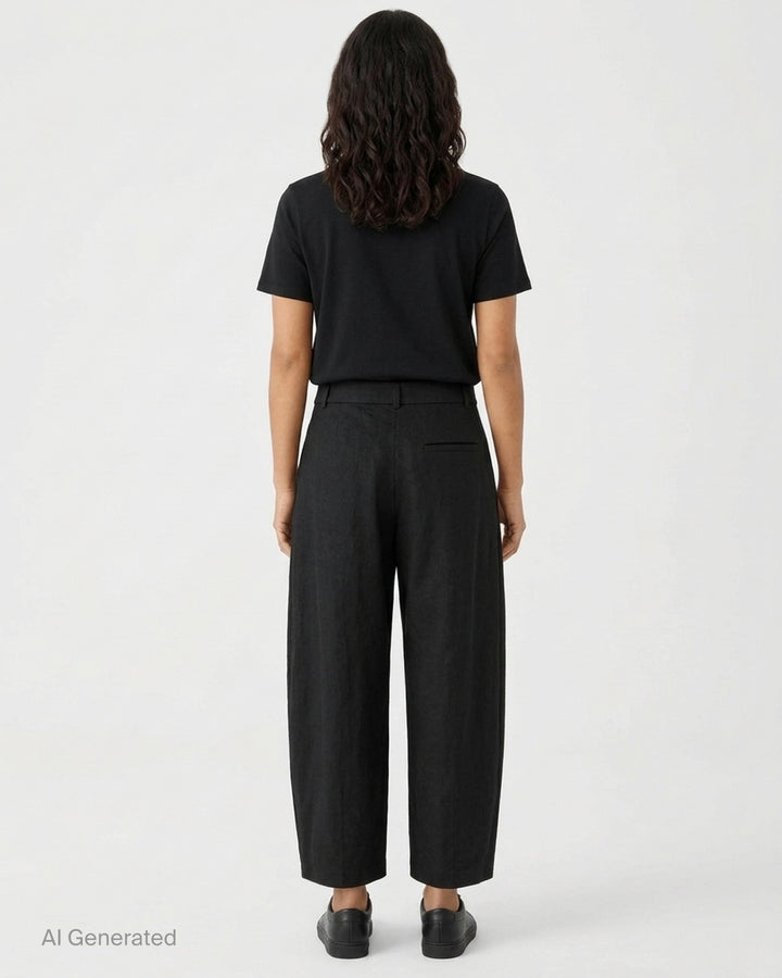 Lauren Manoogian black pleated taper trousers with a high waist and curved leg, shown from the front - back
