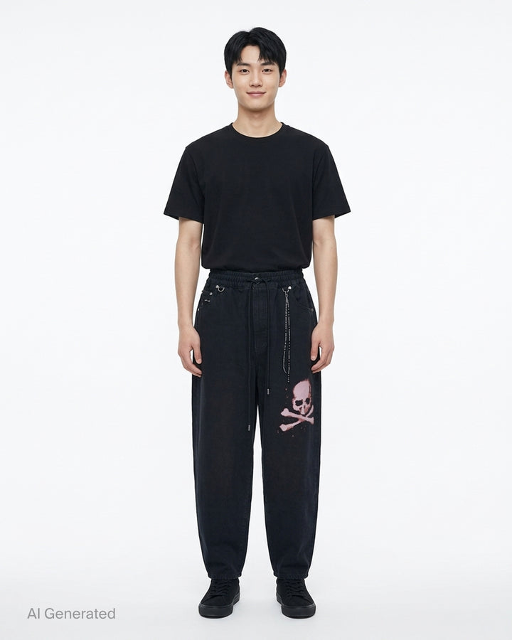 Mastermind wide easy denim pants in washed black with a pink skull and crossbones graphic, drawcord waist and metal D-ring details - front