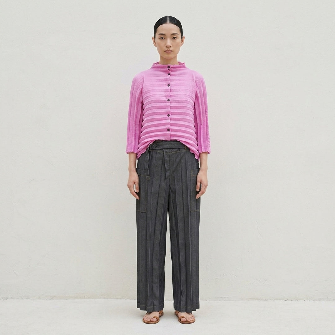 me Issey Miyake Denim Pleats Bottom in grey — wide-leg pleated pants with contrast amber topstitching, asymmetric wraparound waistband, single button closure, and patch pockets - lifestyle