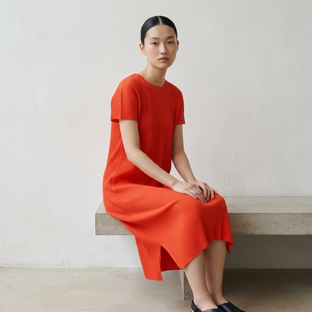 me Issey Miyake Fine Knit Pleats Color 2 midi dress in terracotta, featuring uniform ribbed plissé fabric, short cap sleeves, a round neckline, and side hem slits - lifestyle