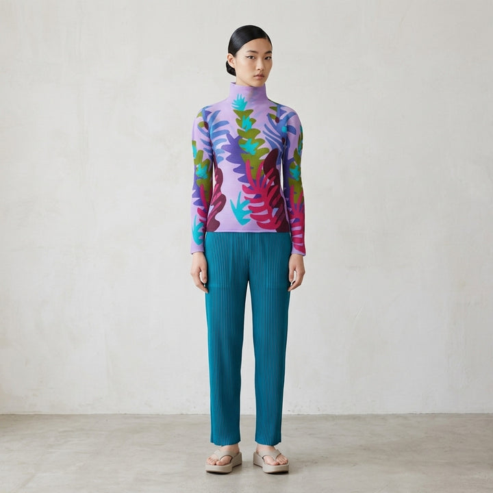 me Issey Miyake Jungle long sleeve turtleneck pleated top with a vibrant abstract botanical print in amber, green, teal, and red tones - lifestyle