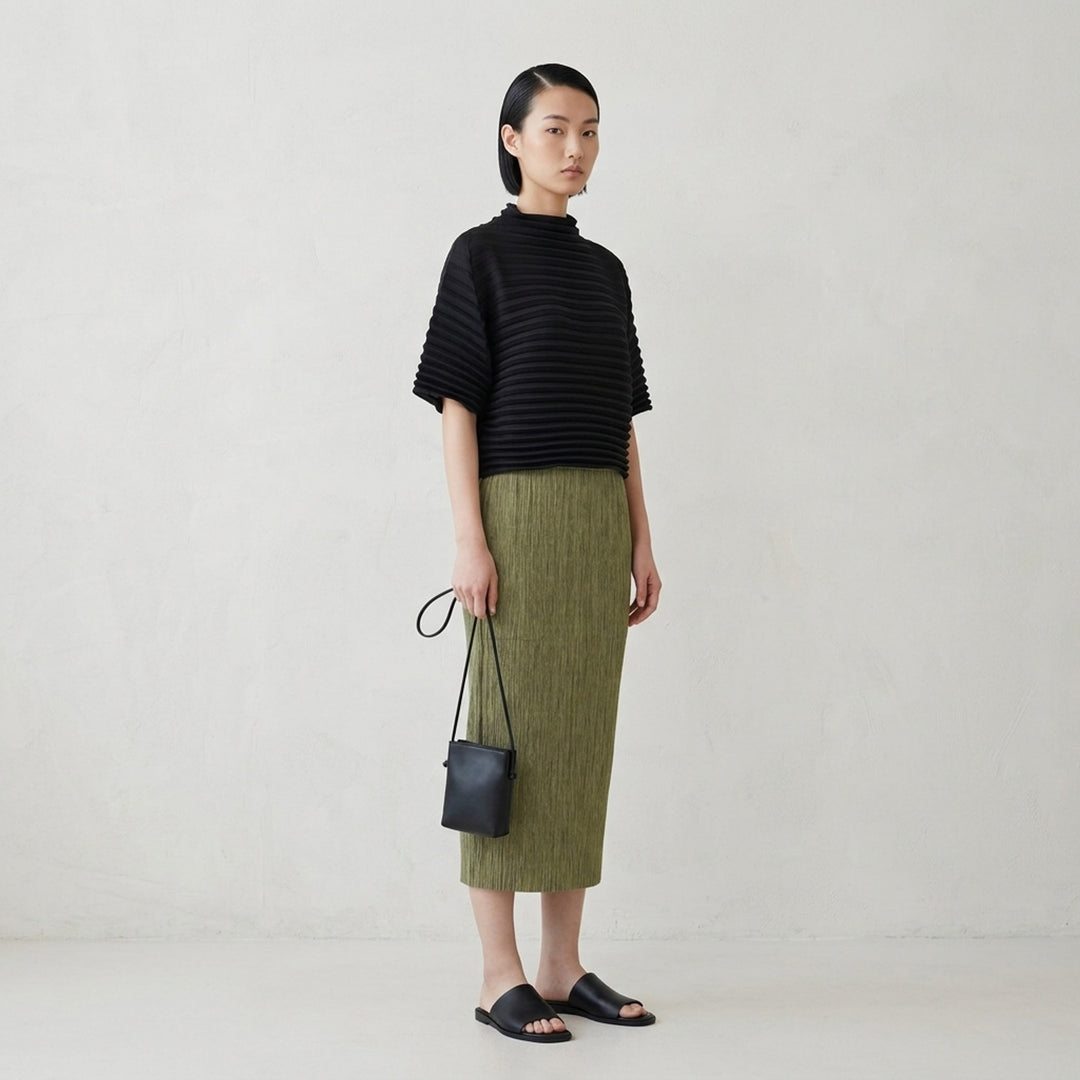 me Issey Miyake black pleated pencil skirt with fine ribbed texture and gathered lower panel, front view - lifestyle