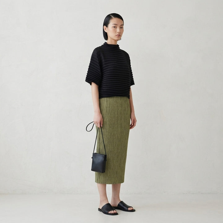 me Issey Miyake black pleated pencil skirt with fine ribbed texture and gathered lower panel, front view - lifestyle