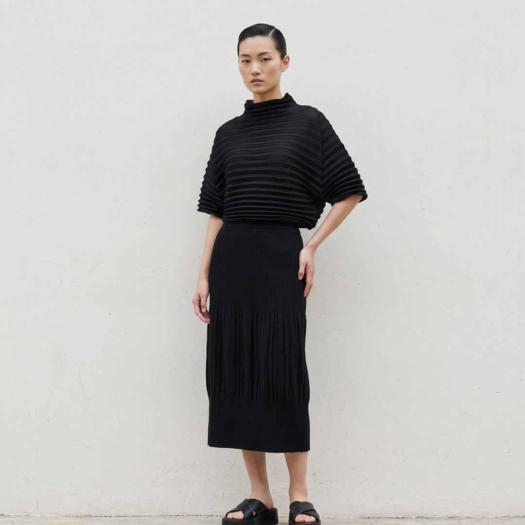 me Issey Miyake black pleated pencil skirt with fine ribbed texture and gathered lower panel, front view - lifestyle