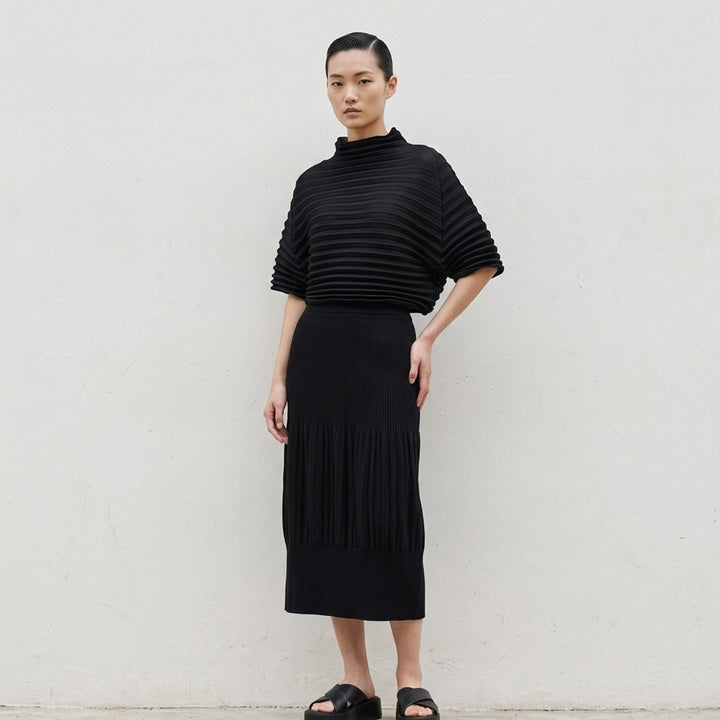 me Issey Miyake black pleated pencil skirt with fine ribbed texture and gathered lower panel, front view - lifestyle