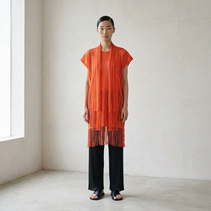 Pleats Please Issey Miyake A-POC LACE black fishnet mesh open-front tunic with draped scarf collar, cap sleeves, and dense knotted fringe hem, displayed flat on white background - lifestyle