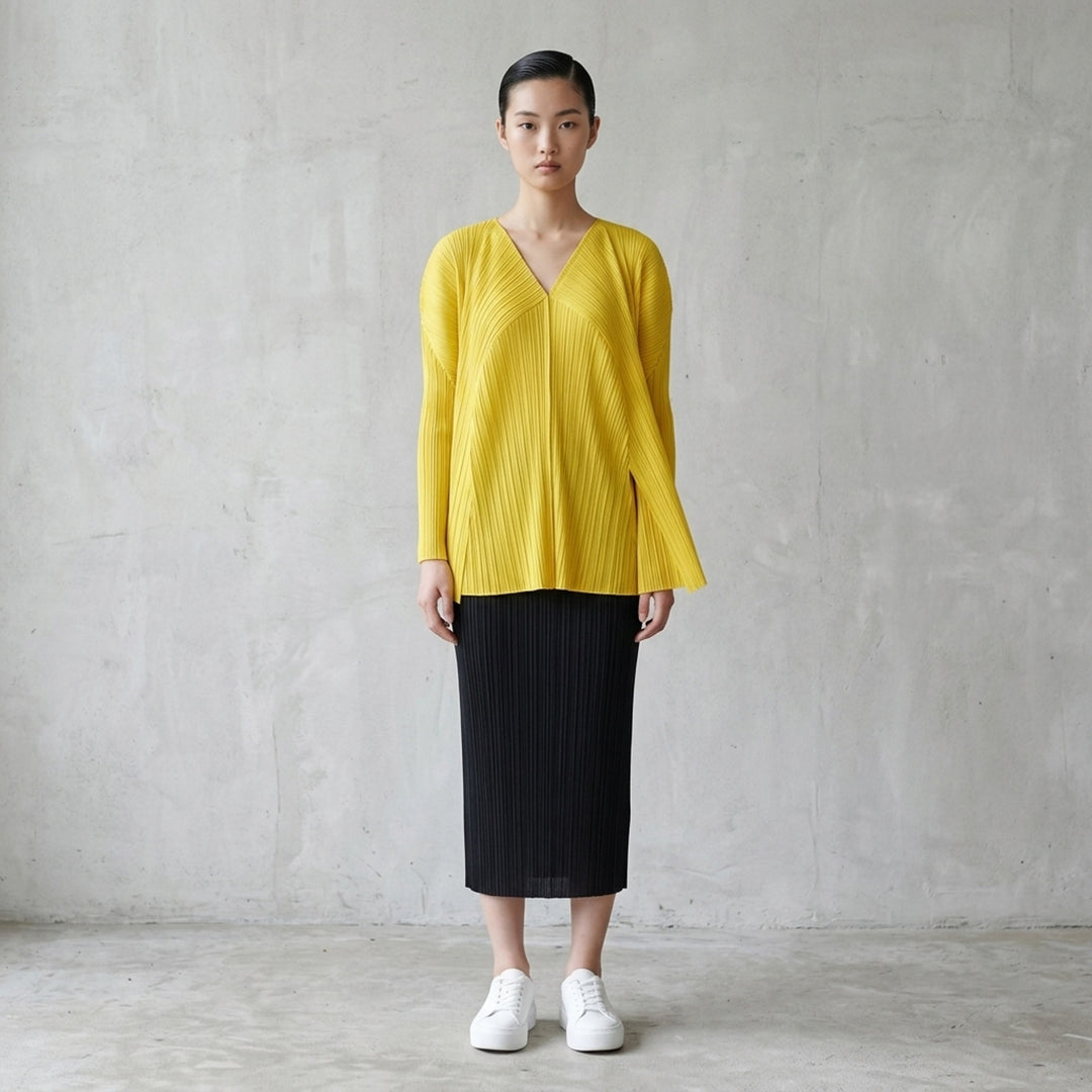 Back view of a sand-toned pleated long-sleeve cardigan from Pleats Please Issey Miyake with pleats fanning across the back - lifestyle