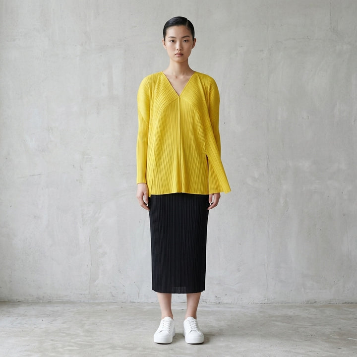 Back view of a sand-toned pleated long-sleeve cardigan from Pleats Please Issey Miyake with pleats fanning across the back - lifestyle