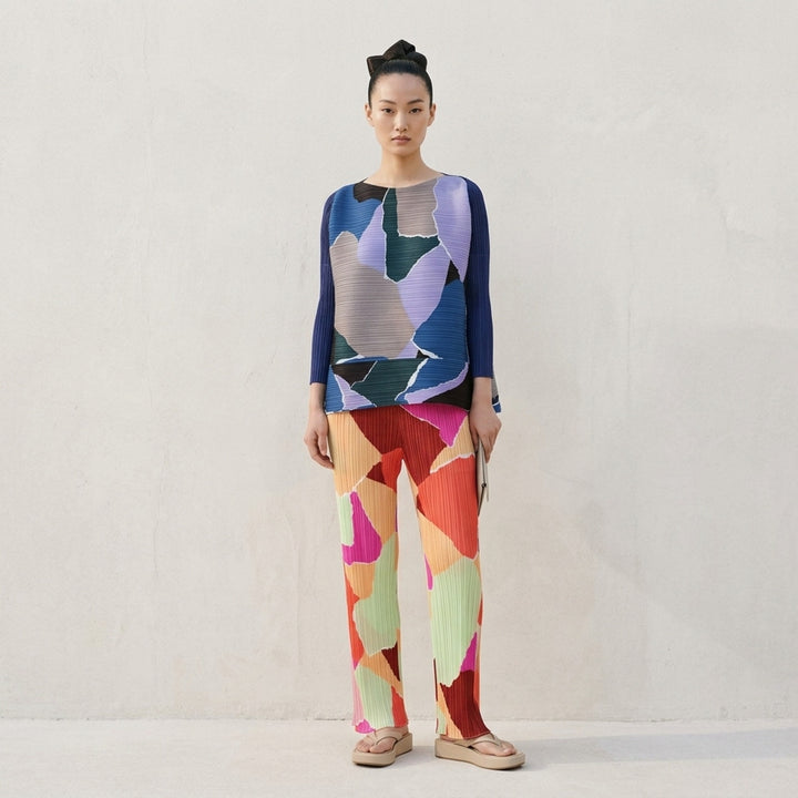 Pleats Please Issey Miyake SURPRISE! Pants in abstract multicolour geometric print featuring fuchsia, burgundy, coral, peach, and sage on permanent-pleat fabric with a straight-leg silhouette - lifestyle