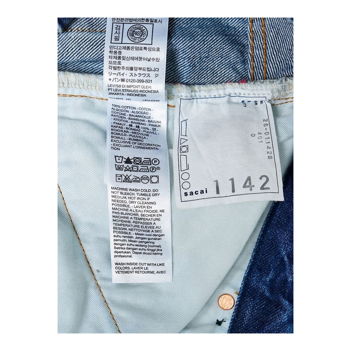 sacai wide-leg washed blue jeans with layered waistband and black belt with metal buckle, shown from the front - packshot