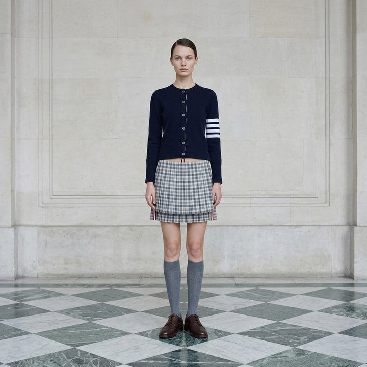 Thom Browne low-rise mini pleated skirt in grey and white gingham check with layered hem and red, white, and blue grosgrain trim - lifestyle