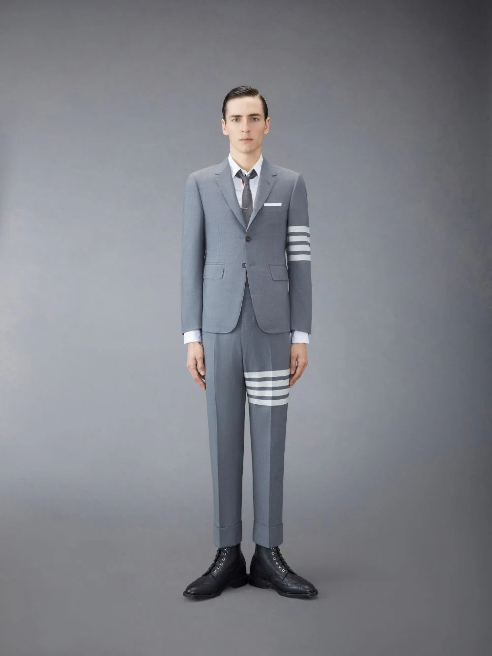 Thom Browne Classic Engineered Blazer in medium grey with four white bar stripes on the sleeve and red, white, and navy striped lining