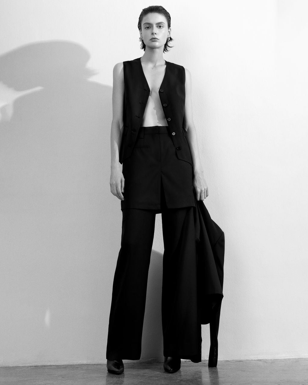 Club21 Collection Iris Sartorial Wool Mix Vest in taupe, featuring a V-neckline, five tonal buttons, hip flap pockets, and a crossover hem, displayed flat on a white background